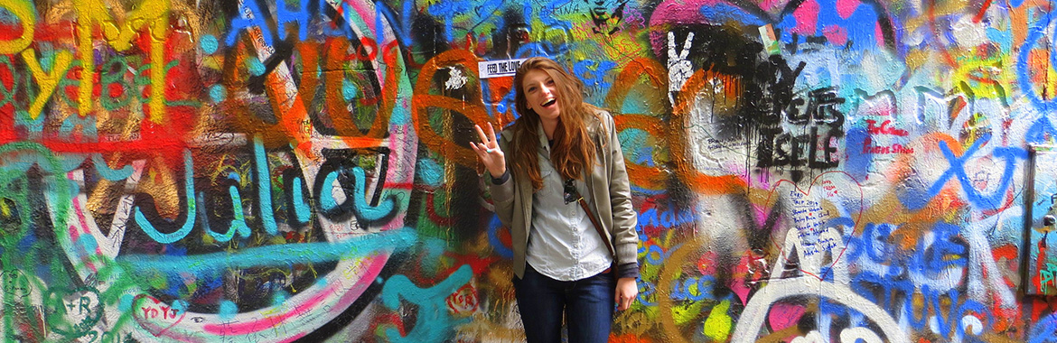 Person giving the forks up if front of a wall of graffiti