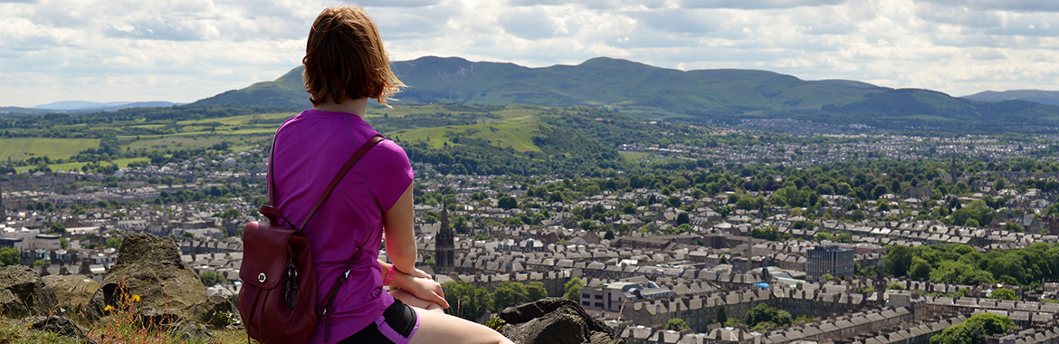 person sitting on a hill overlooking town