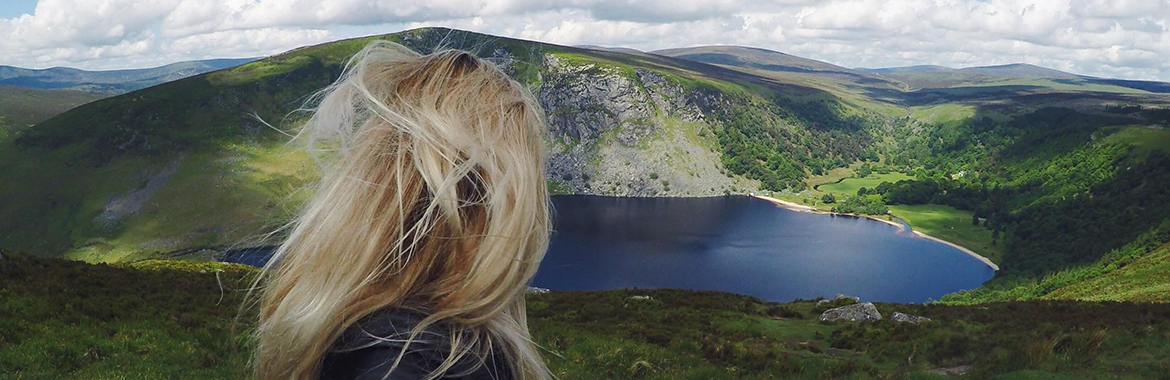 Person standing on a mountain staring a body of water