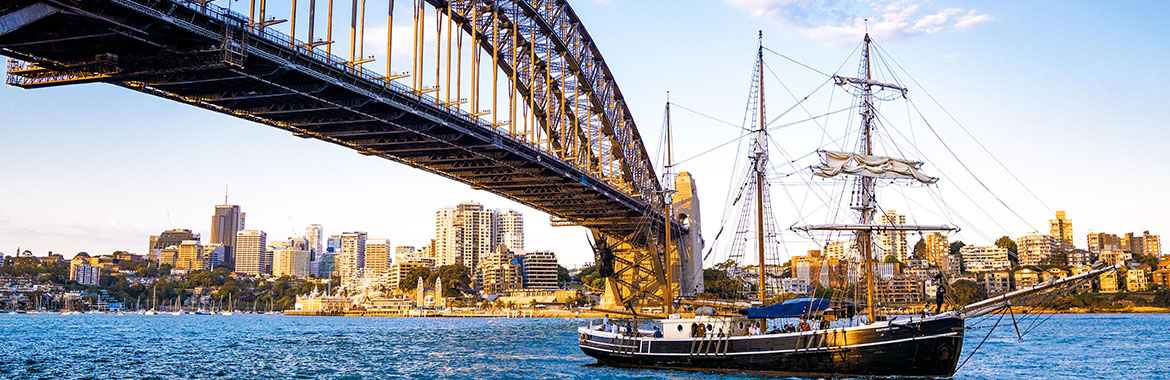 Old boat sailing on the water underneath a bridge