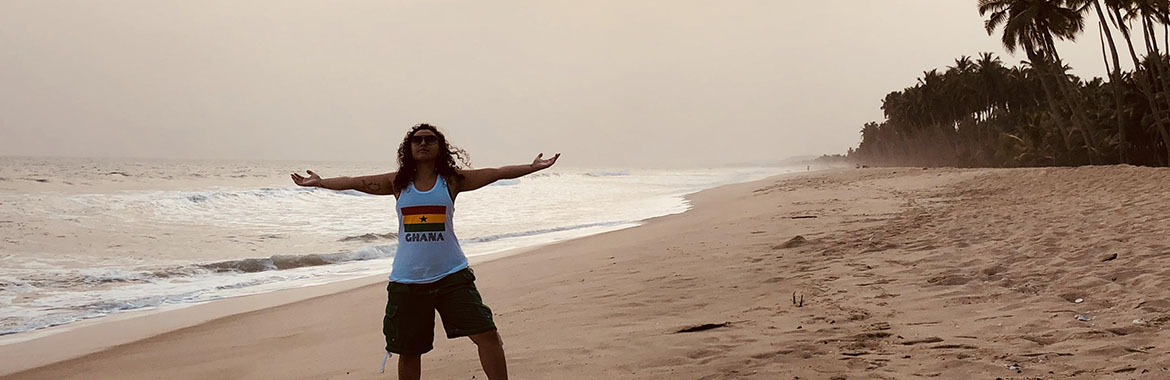 Person standing on a beach with their arms spread wide 
